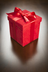 Red Gift Box with Ribbon and Bow Resting on Wood
