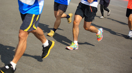 Naklejka premium Unidentified marathon athletes legs running on street 