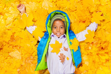 African boy laying in autumn maple leaves