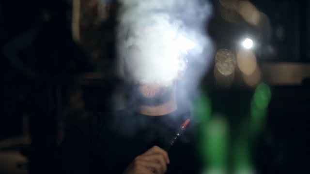 brutal man smokes a hookah in a cafe in the evening