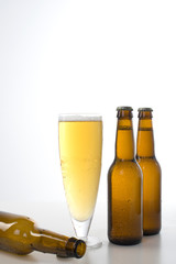 Two brown beer bottles and a full glass of beer.