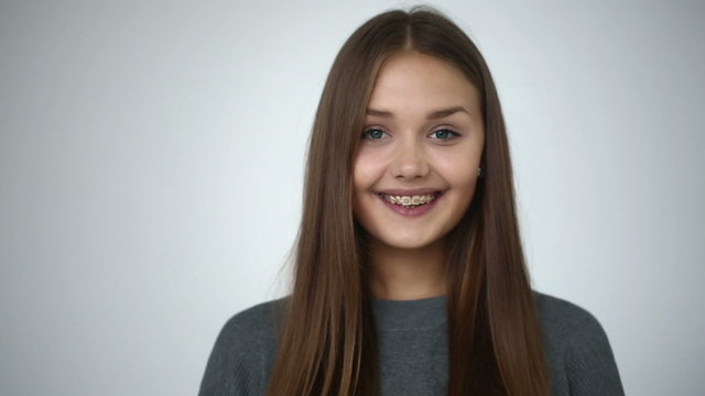 Young girl with braces on teeth looking at camera and smiling.