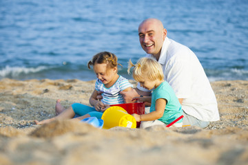Fototapeta premium girls with dad playing on sea shore