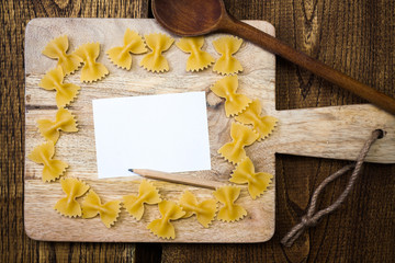 Note for recipe with pasta on wooden cutting board