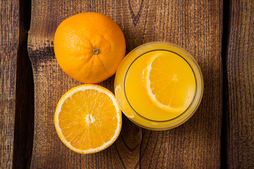 Orange fruit and glass of juice, wooden background, top view