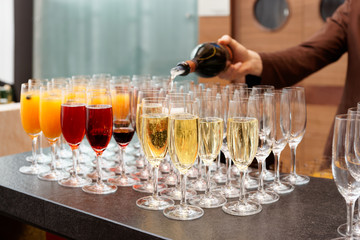Bartender is pouring sparkling wine in glasses