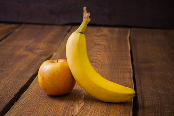 Apple and banana fruits on dark wooden table