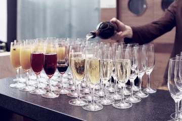 Gordijnen Bartender is pouring sparkling wine in glasses, toned image © Kondor83