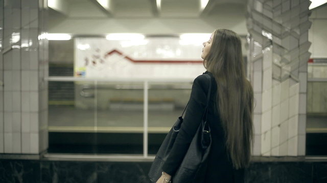 Girl waiting for the subway train waits and comes aboard