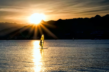 Windsurfer sailing in the sea at sunset