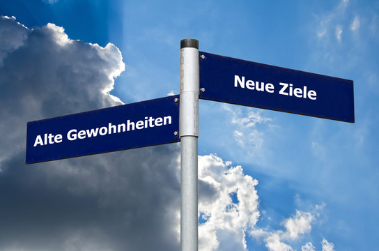 Straßenschild vor bewölktem/blauen Himmel mit Schriftzug 'Alte Gewohnheiten' vs. 'Neue Ziele'
