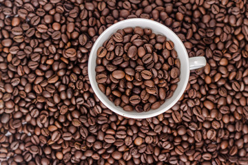Cup with coffee beans on background of coffee bean, top view
