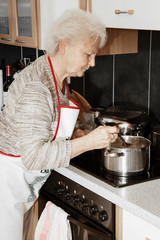 Elderly woman in cooking in the kitchen
