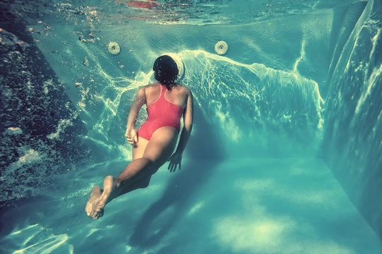 Girl swimming underwater in pool.