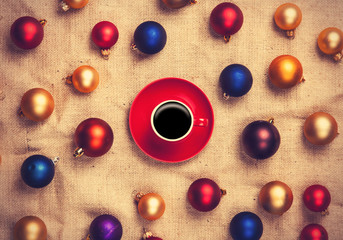 Hot coffee and christmas balls on jute background.