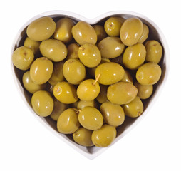 Green olives in plate in the form of heart on a white