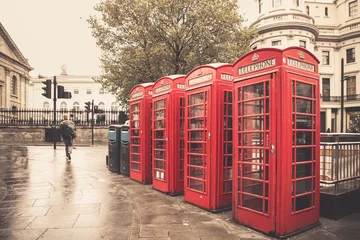 Fotobehang Vintage stijl rode telefooncellen op regenachtige straat in Londen © littleny
