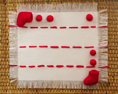 red boots and beads on a linen napkin  with red stitches