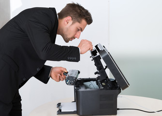 Young Businessman Fixing Cartridge In Photocopy Machine