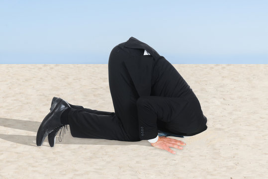 Businessman Hiding His Head In Sand