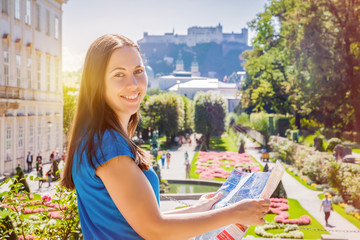 Obraz premium Uśmiechnięta dziewczyna z mapą miasta w ogrodzie Mirabell w Salzburgu