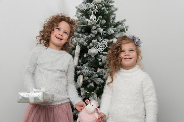 Two cute child girls with gifts, Christmas tree