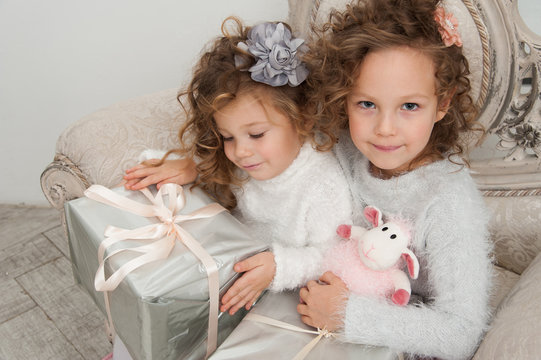Two child girls with gifts on coach at Christmas time