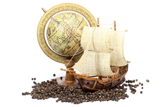 Pfefferkörner mit Segelschiff und Globus isoliert auf weißem Hintergrund	