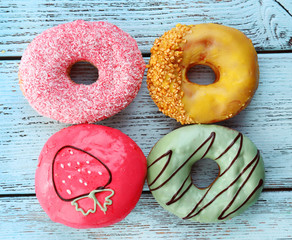 Delicious donuts with glaze on colorful wooden background