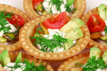 Tartlets with greens and vegetables with sauce on plate
