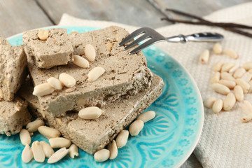 Sunflower halva with peanuts on plate, on wooden background