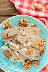 Sunflower halva with nuts on plate, on wooden background
