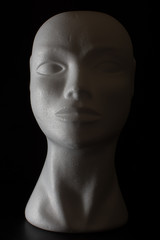 Mannequin head isolated on a black background with side lighting