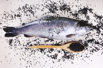 Fresh fish and spices in spoon on wooden background