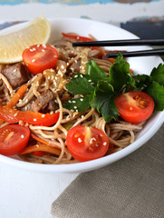 Chinese noodles with vegetables and roasted meat in bowl