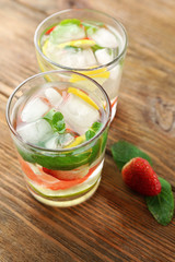 Summer cocktail with ice cubes on wooden table
