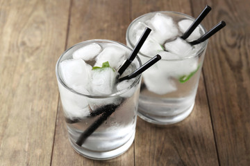 Glass of water with ice cubes on wooden table