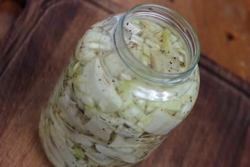 Jar of herrings with chopped onion on a wooden board..