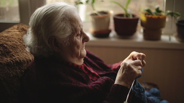 The old woman sits at home and knits garments