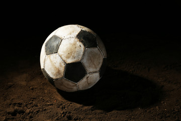 Fototapeta na wymiar Soccer ball on ground on dark background