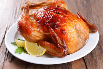 Delicious baked chicken on plate on table close-up