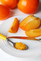 Ripe persimmons on plate, on wooden background