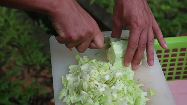 man with a knife cut the cabbage on white board	