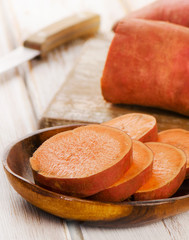 Sweet potatoes on a wooden background .