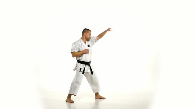 Karate. Man in a kimono hits foot on the white background. Slow