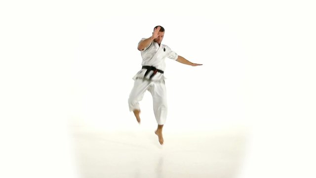 Karate. Man in a kimono hits foot on the white background. Slow