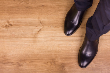 Legs of businessman on parquet, top view