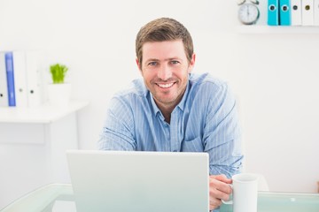 Smiling businessman holding mug at desk