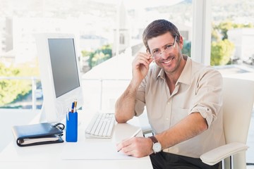 Fototapeta premium Smiling casual businessman working at his desk
