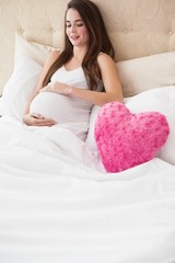 Obraz na płótnie Canvas Pregnant brunette sitting in bed